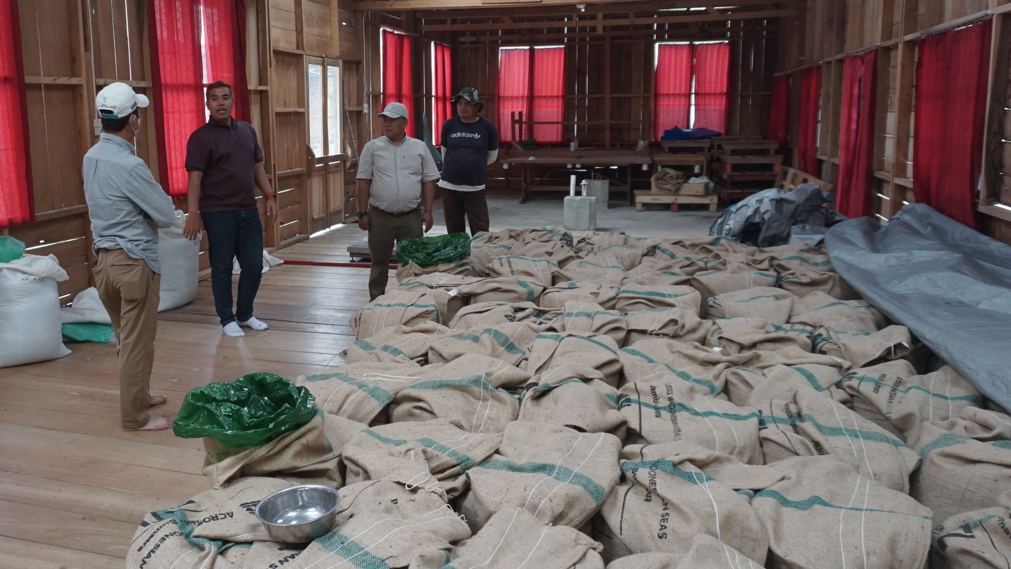 Jute bags stencilled Across Indonesian Seas on the warehouse floor in Kerinci, with the Agrotropik Nusantara team